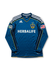 LAギャラクシー 2007-08 アウェイジャージの正面、ブルーボディ、HERBALIFEロゴ、LA Galaxyエンブレム、MLSパッチ、アメリカ国旗パッチ、白い肩ラインが見える長袖デザイン