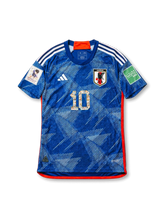 日本代表 2022 ホームジャージ キャプテン翼10番の正面、ジャパンブルーボディ、折り紙風グラフィック、JFAエンブレム、漫画キャラクター柄入り10番、カタール大会パッチが見えるデザイン