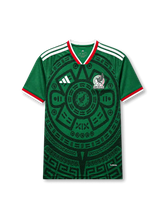メキシコ代表2026ホームジャージ正面、グリーンボディ、古代意匠風の大きな円形グラフィック、ホワイトの肩3ストライプ、代表エンブレム、Vネック、半袖デザイン