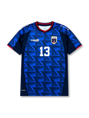 カーボベルデ代表2026-27ホームユニフォーム前面・ロイヤルブルーとネイビーの幾何学トライアングル柄、ネイビー×レッドのVネックと袖トリム、中央に白の背番号13、左胸Capelli Sportロゴ、右胸にサメのFCFエンブレム