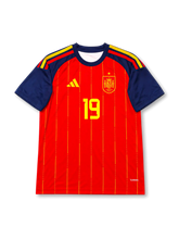 スペイン代表 2026 ワールドカップ ホーム レプリカユニフォーム フロント、赤ボディにイエローピンストライプ、ネイビーの袖と肩の国旗色ストライプ、右胸にイエローのスペイン連盟エンブレムと星、イエローの胸番号19