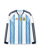 アルゼンチン代表 2026-27 ホーム 長袖レプリカユニフォーム フロント、空色と白の縦縞ストライプ、右胸に3つ星ゴールドAFA刺繍エンブレムとFIFAワールドチャンピオンズバッジ、ゴールドのパフォーマンスロゴ、長袖のネイビー3ストライプとリブカフス