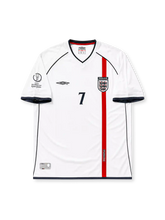 ホワイトベースにネイビーの襟と裾ラインを配し、右袖にFIFAワールドカップ韓国・日本2002大会エンブレム、裾中央にイングランドの十字紋章タブを備え、背面にネイビーのBECKHAMネームと7番をあしらったイングランド代表2002ワールドカップホームジャージ背面