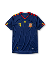 ネイビーベースに肩のイエロー×レッド2本ラインを配し、胸にadidasロゴ、イエローの9番、スペインサッカー連盟のクラブエンブレム、裾にCLIMACOOL表記を備えたスペイン代表2010ワールドカップアウェイジャージ正面