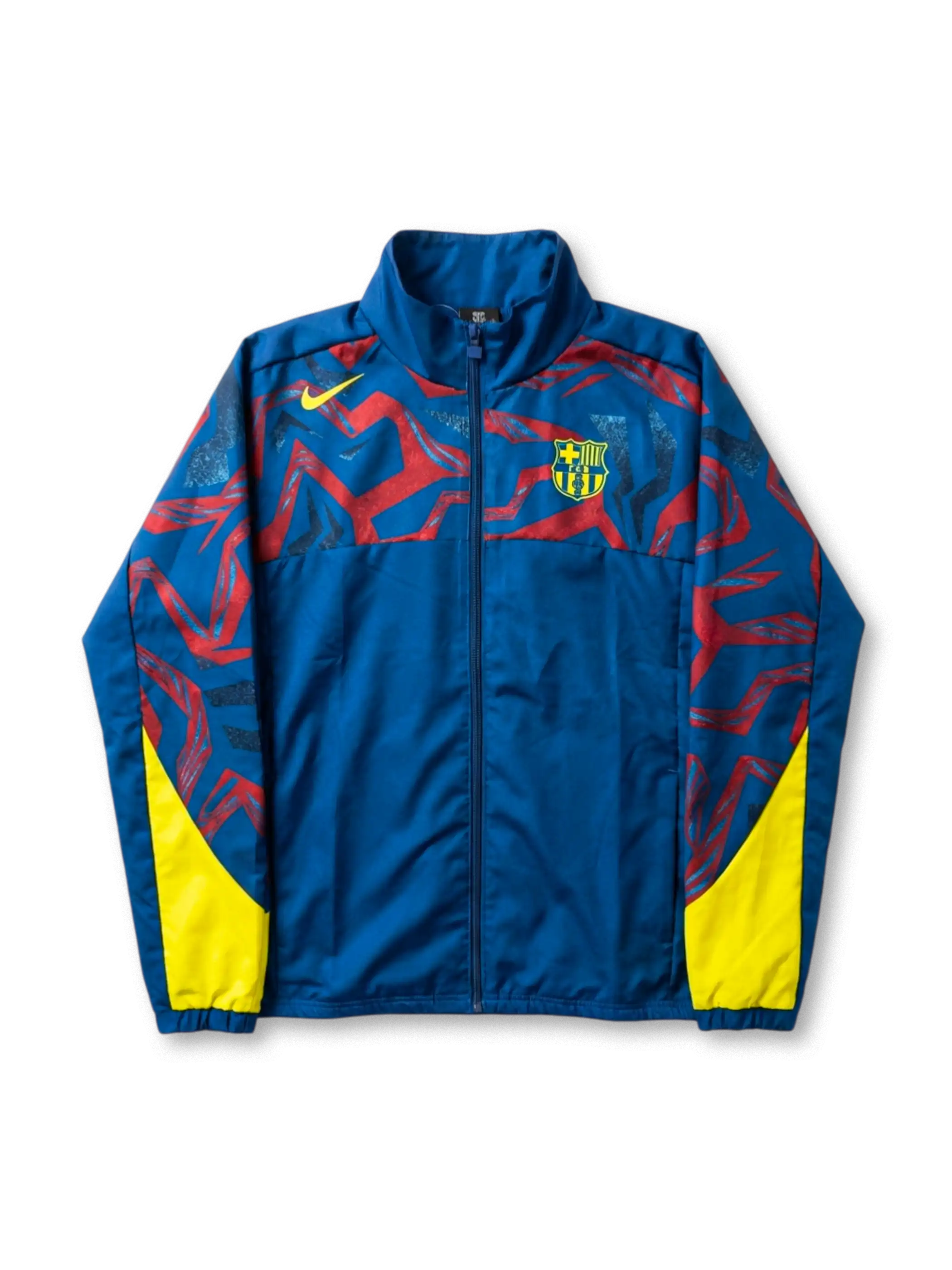 FCバルセロナ Nike グラフィックウィンドブレーカー ロイヤルブルー 前面 — レッド抽象グラフィックパターンとイエロー脇パネル、盾形エンブレム刺繍を配した公式トレーニングライン