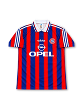 バイエルン・ミュンヘン 1995〜1997年 ホームユニフォーム ローター・マテウス10番。adidas製のレッドとロイヤルブルーの縦ストライプに、ホワイトのポロカラーと肩のスリーストライプを組み合わせたレトロサッカージャージ。胸元にはadidasロゴ、バイエルンのクラブエンブレム、ホワイトのOPELスポンサーロゴを配置。背面にはBAYERN MÜNCHENの文字、ホワイトの10番、MATTHÄUSのネームを配したデザイン。