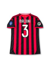 ACミラン パオロ・マルディーニ3番 レガシーエディションユニフォーム。adidas製の伝統的なレッドとブラックの縦ストライプに、ブラックの袖、ホワイトの折り襟、レッドの肩のスリーストライプを組み合わせたレトロサッカージャージ。胸元にはadidasロゴ、ACミランのクラブエンブレム、bwinスポンサーロゴを配置。袖には欧州7度制覇を記念するパッチとリーグパッチを備え、背面にはMALDINIのネームと3番、襟下には筆記体のAC Milanロゴをあしらった特別記念デザイン。