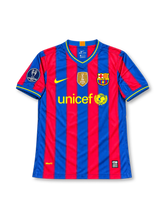 FCバルセロナ 2009-10シーズン ホームユニフォーム ズラタン・イブラヒモビッチ9番 Nike製 ブルーとエンジの縦ストライプ、イエローの縁取りを施したVネックと袖口、イエローのNikeスウッシュとUNICEFロゴ、FCバルセロナのクラブエンブレム、胸元のFIFAクラブワールドカップ優勝記念バッジ、UEFAチャンピオンズリーグの袖章、背面にIBRAHIMOVIĆのネームとイエローの9番を配したレトロサッカージャージ