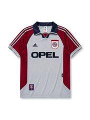 グレー地にマルーンのラグラン袖とグレーマルーンのadidasスリーストライプ、ネイビーのVネック襟、左胸のadidasロゴ、右胸のFCバイエルン・ミュンヘンエンブレム、中央のOPELスポンサーロゴを備えたバイエルン・ミュンヘン1998-99アウェイジャージ正面