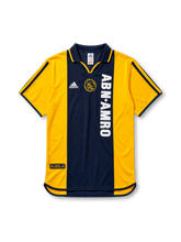 イエローの肩袖にネイビーの中央パネル、左胸のadidasロゴ、中央のAJAXクラブエンブレム、縦書きの白いABN・AMROスポンサーロゴを備えたアヤックス2000/01アウェイジャージ正面