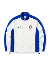 白地にライオンブルーの切り替えパネル、緑のNikeスウッシュ、4つの星を戴いたCBFエンブレムと「BRASIL」の文字を備えたブラジル代表1998リイシュートラックジャケット正面
