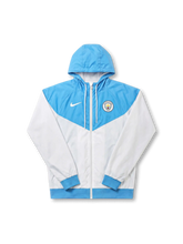 マンチェスター・シティ Nike ウィンドランナージャケット スカイブルー/ホワイト — 逆V字パネル切替と円形エンブレム刺繍を配した公式トレーニングライン
