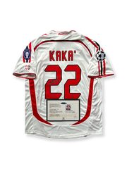 製品画像：「2006-07シーズン ACミラン カカサイン入り 22番クラシックアウェイユニフォーム 正面展示。カカ直筆サイン、クラシックアウェイデザイン、ヨーロッパチャンピオンズリーグ ワッペン、高密度刺繍、吸汗性・通気性に優れた快適素材でファン必携。」

詳細画像：「ACミランのエンブレム刺繍、カカのサイン、ユニフォーム背面のディテールの拡大。カカ記念品としてファンやコレクターに人気。」