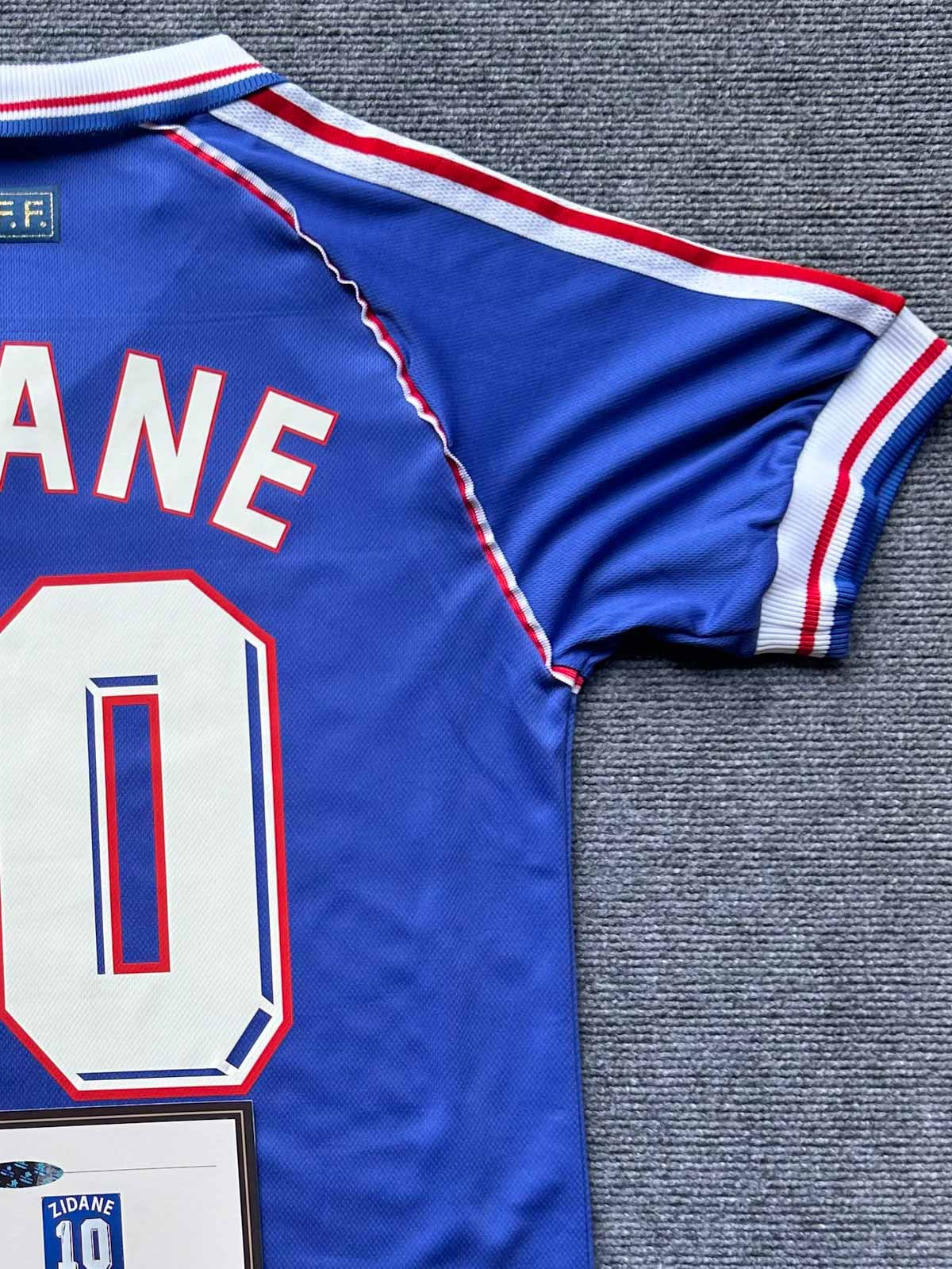 製品画像：1998年フランス代表ホームユニフォーム、ジネディーヌ・ジダンサイン入り10番、レトロデザイン、フランスワールドカップ優勝記念

詳細画像：ジネディーヌ・ジダンの高密度刺繍名、10番の手作業フロッキープリントのディテール

モデル画像：1998年フランス代表ユニフォームの着用イメージ、フロッキープリントと刺繍の質感を強調