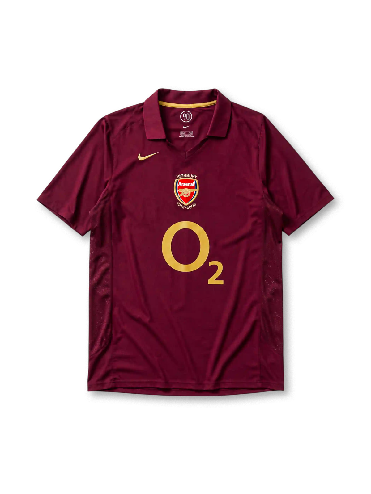レッドカラント地にゴールドパイピングのポロ襟、左胸のゴールドNikeスウッシュ、中央のHIGHBURY 1913-2006記念エンブレム、大きなO2スポンサーロゴ、両脇のメッシュ通気パネルを備えたアーセナル2005-06ホームジャージ正面